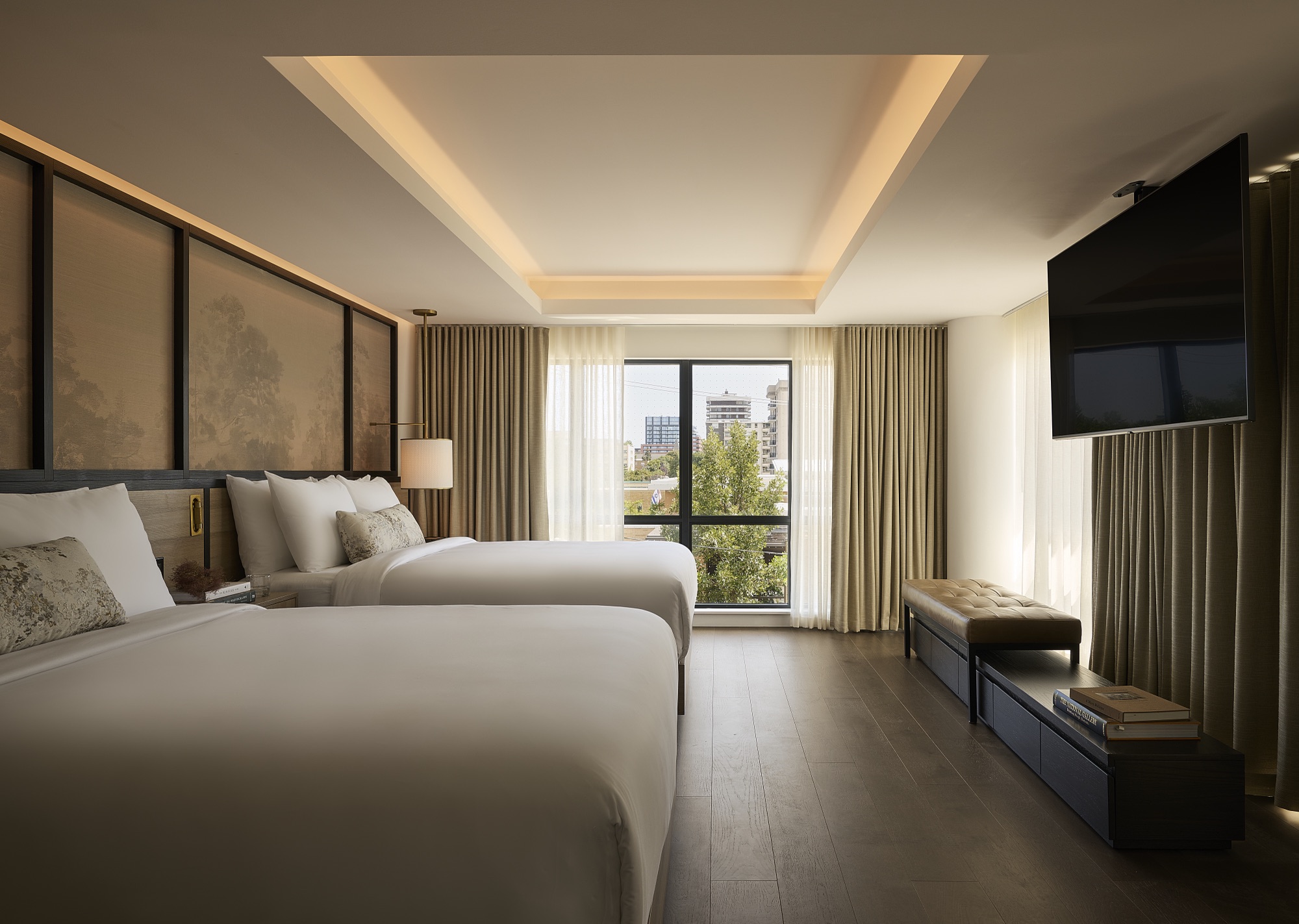 A guestroom at Glenhill Hotel with two queen beds and a window overlooking the neighbourhood
